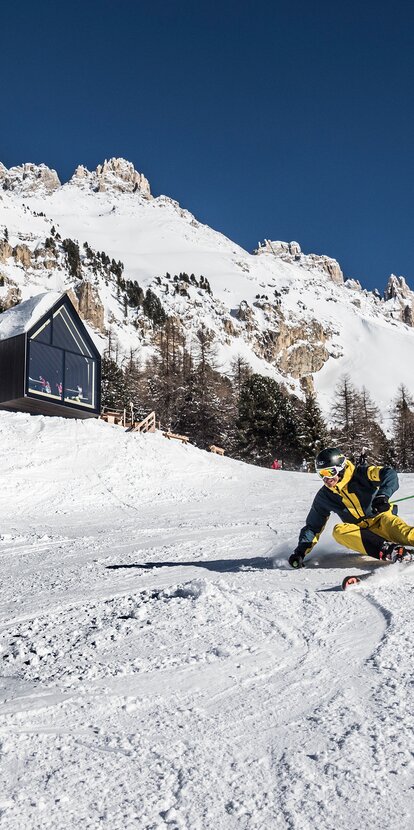 Skifahrer macht Kurve vor der Berghütte Oberholz | © Ph. P.Codeluppi